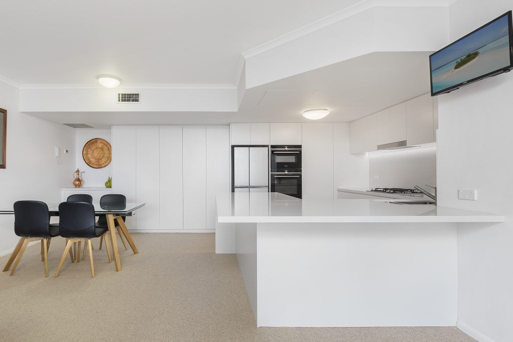 AFTER Manly Renovation - Satin Polyurethane Kitchen with electronic push open drawers and a Quantum Quartz stone benchtop and splashback in Michelangelo