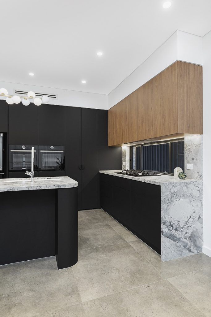 Chipping Norton, Matt black kitchen featuring Super White Stone benches and a curved edge island