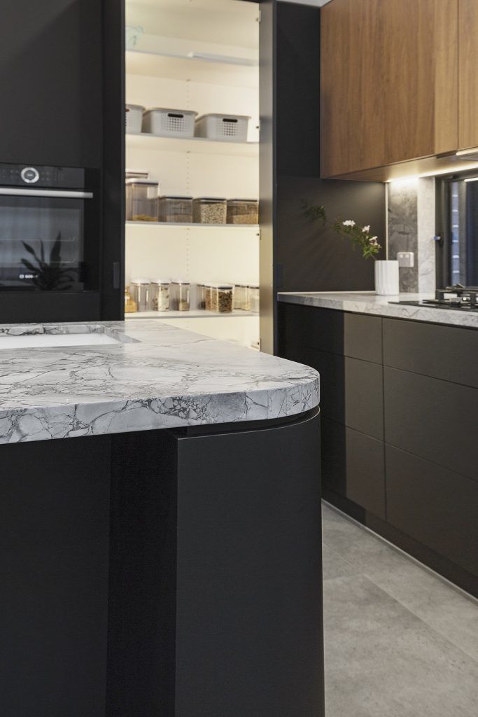 Chipping Norton, Matt black kitchen featuring Super White Stone benches and a curved edge island