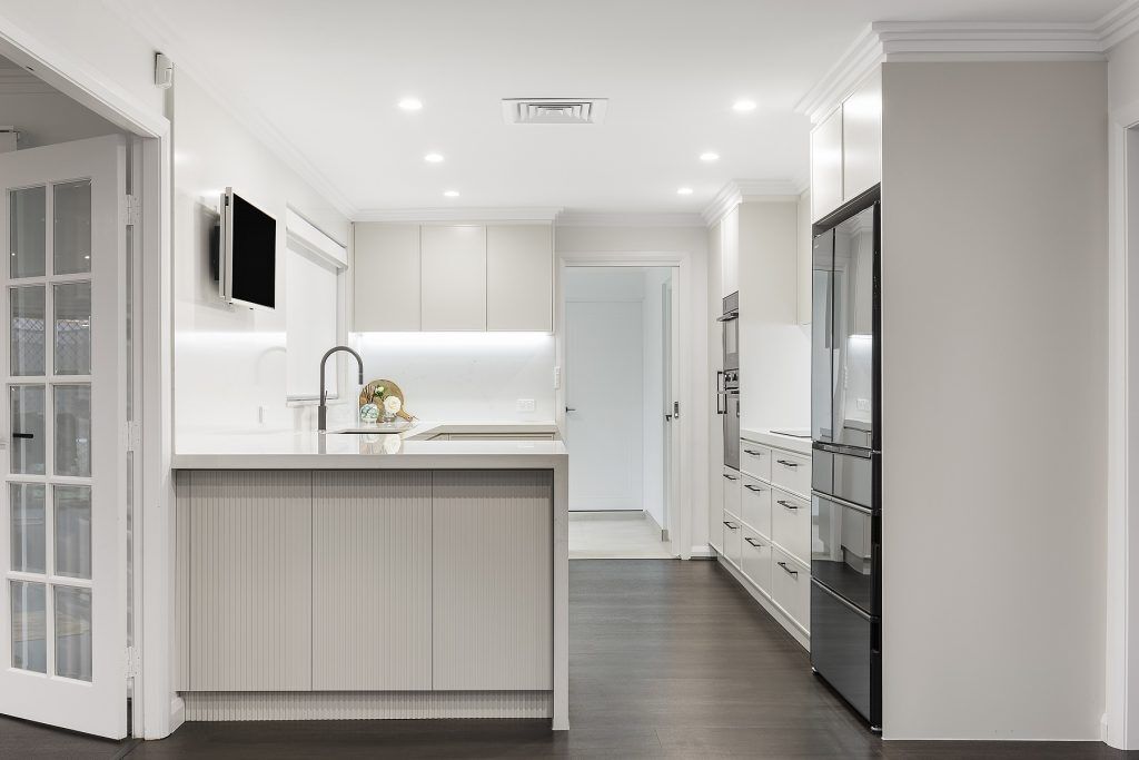 AFTER Moorebank Renovation, Polyurethane Thin Shaker kitchen with a stone benchtop and featuring a fluted paneled breakfast bar
