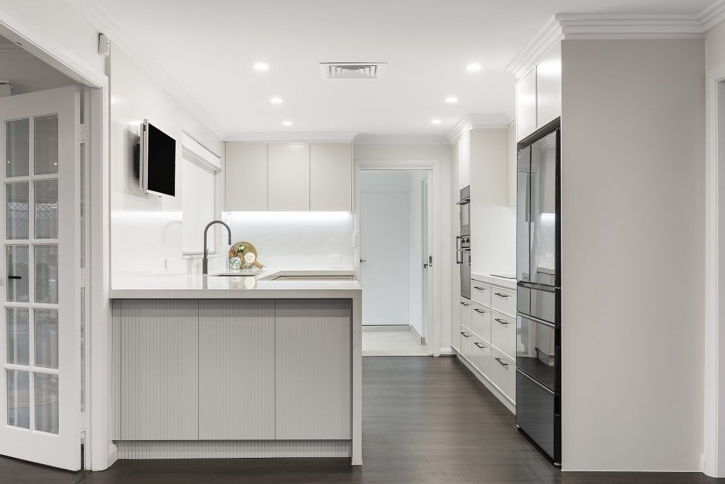 Moorebank, Polyurethane Thin Shaker kitchen with a Quantum Quartz stone benchtop and splashback in Michelangelo and featuring a fluted paneled breakfast bar