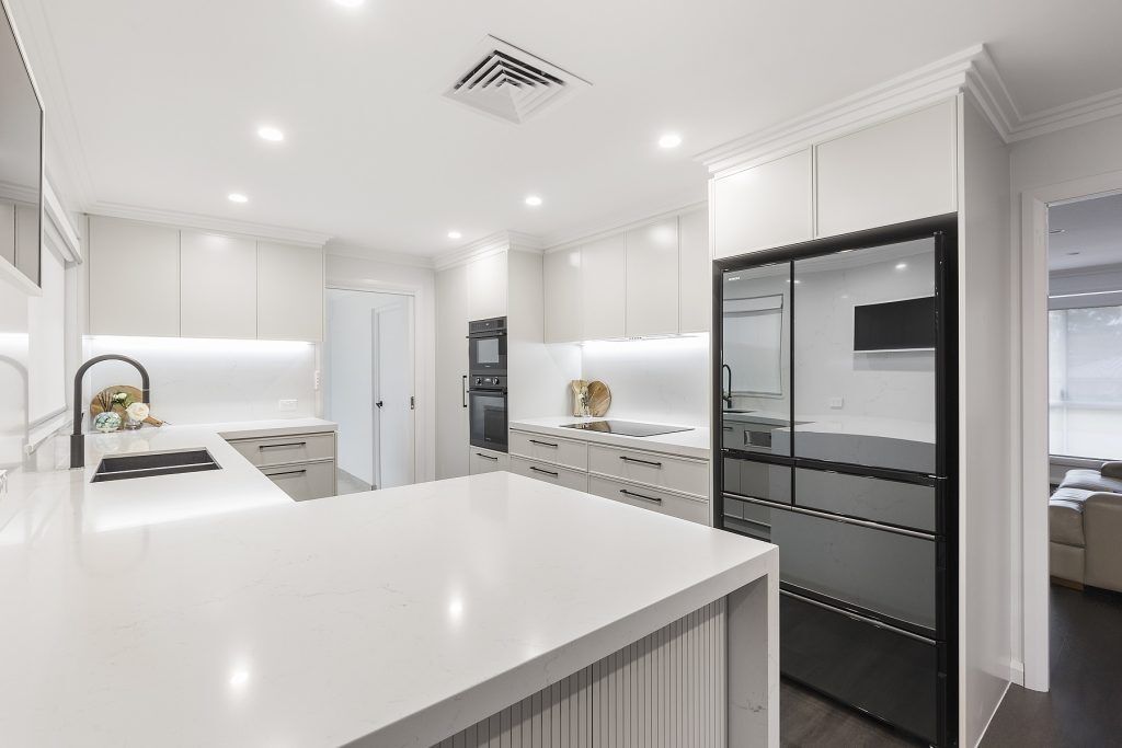 Moorebank, Polyurethane Thin Shaker kitchen with a Quantum Quartz stone benchtop and splashback in Michelangelo and featuring a fluted paneled breakfast bar